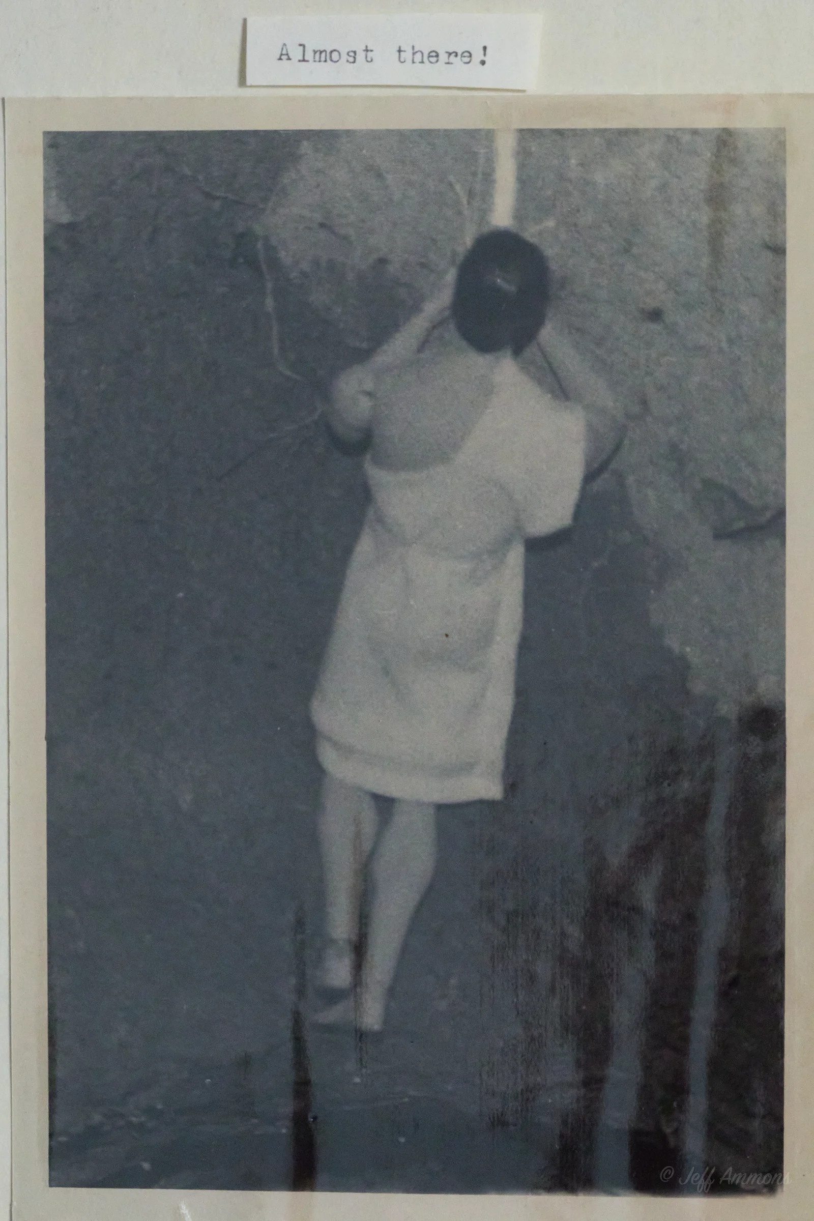 Heracles climbs down a rope into a dark cave opening.