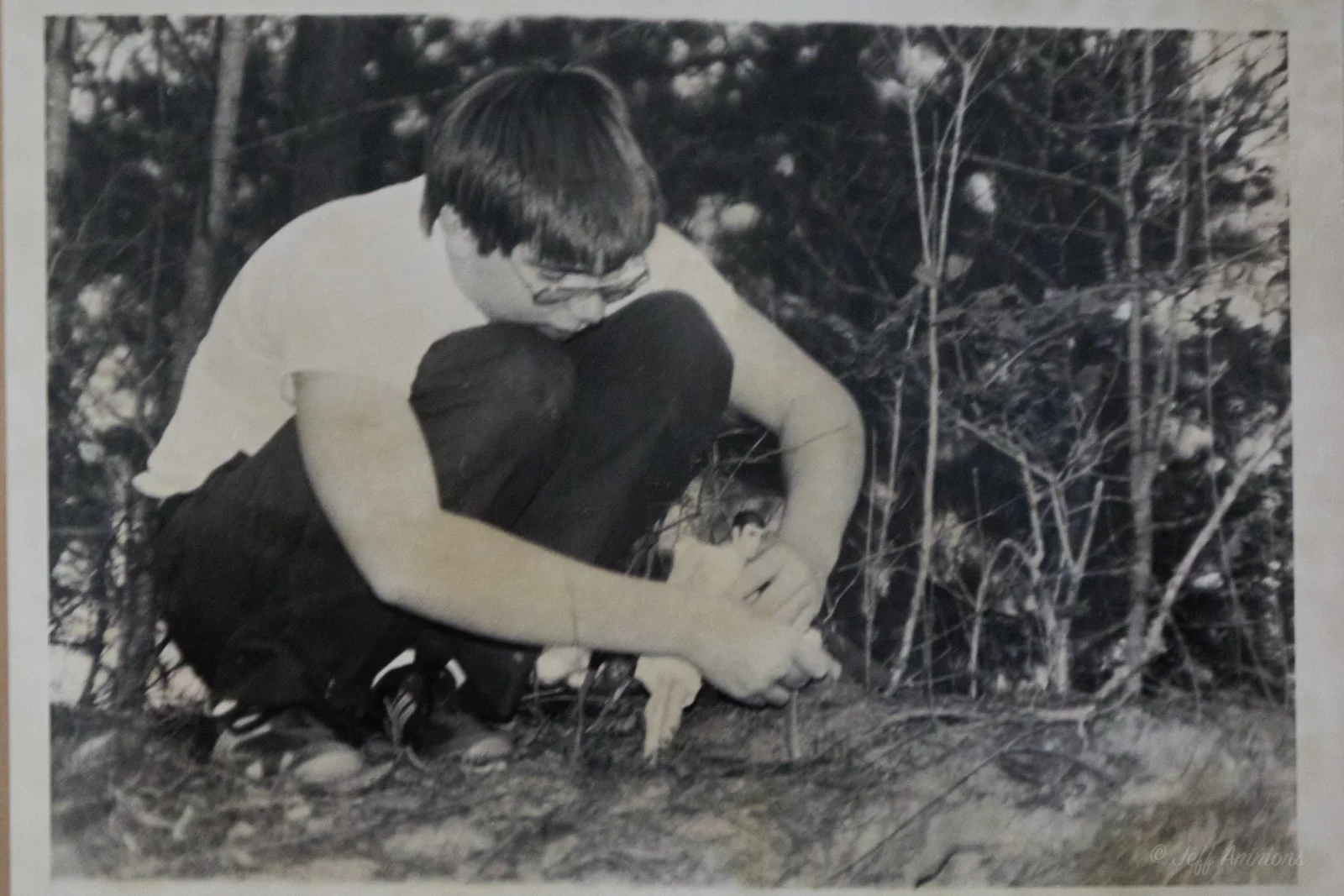 A young photographer crouches in the woods, carefully positioning the action figures for a shot.